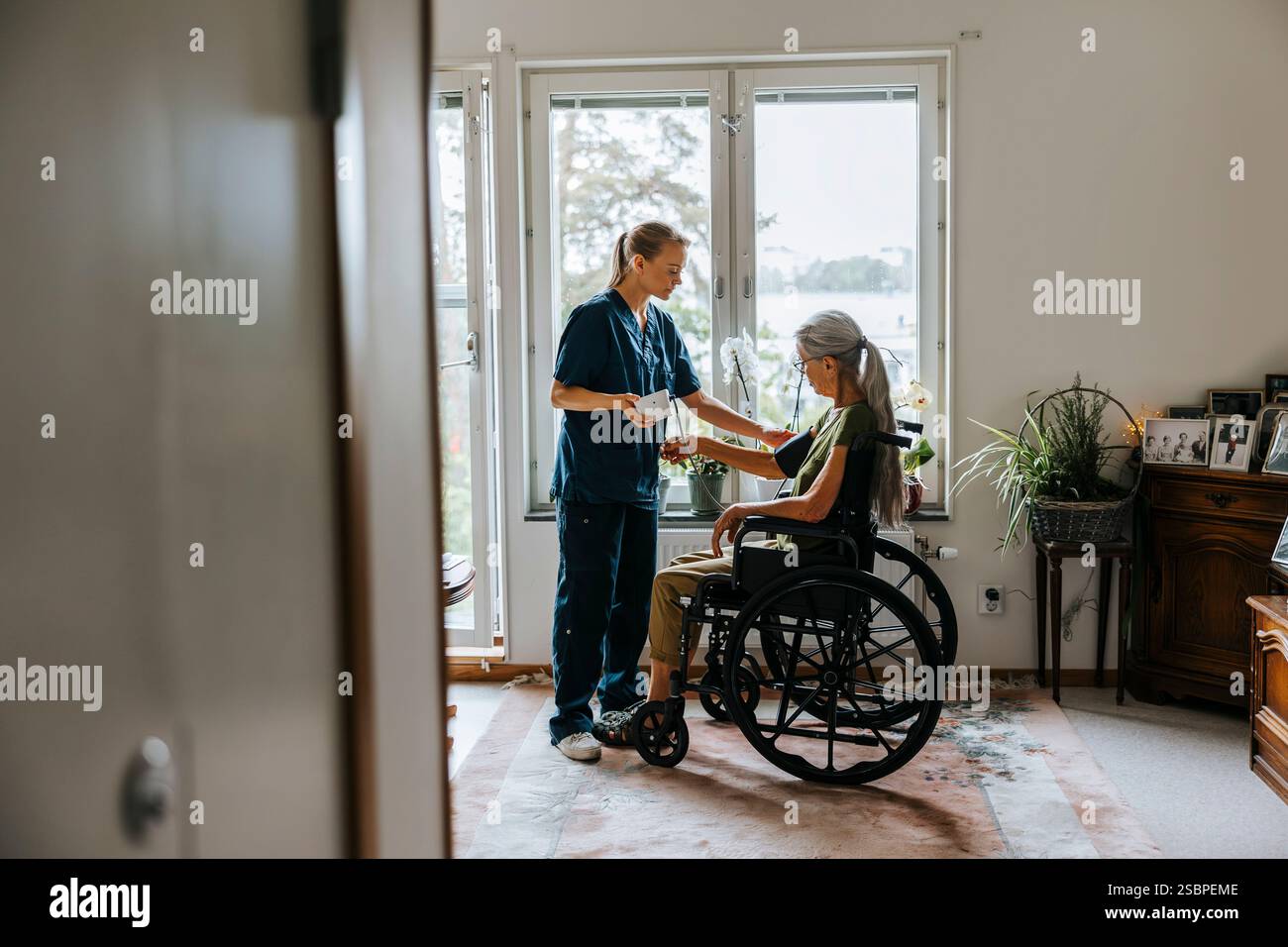 Female medical expert checking blood pressure of elderly woman with ...