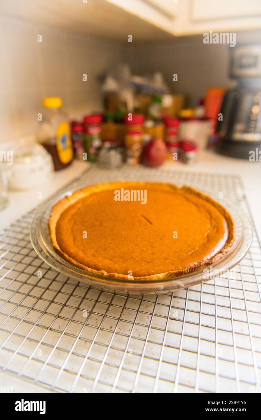 Pumpkin pie cooling on rack with out of focus spice containers in the ...