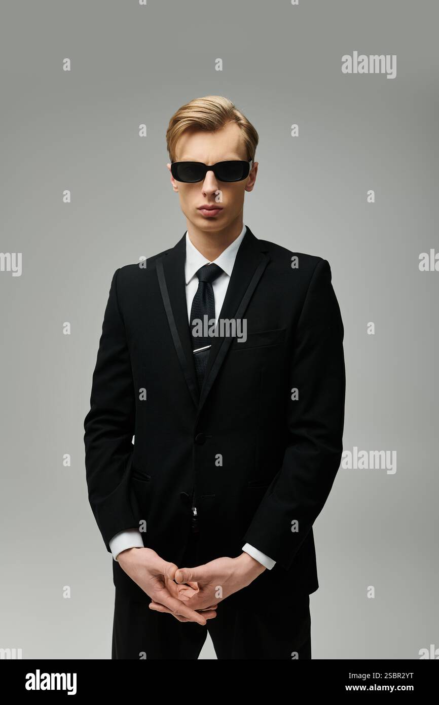 Stylish young man stands confidently with sunglasses and a sharp black ...