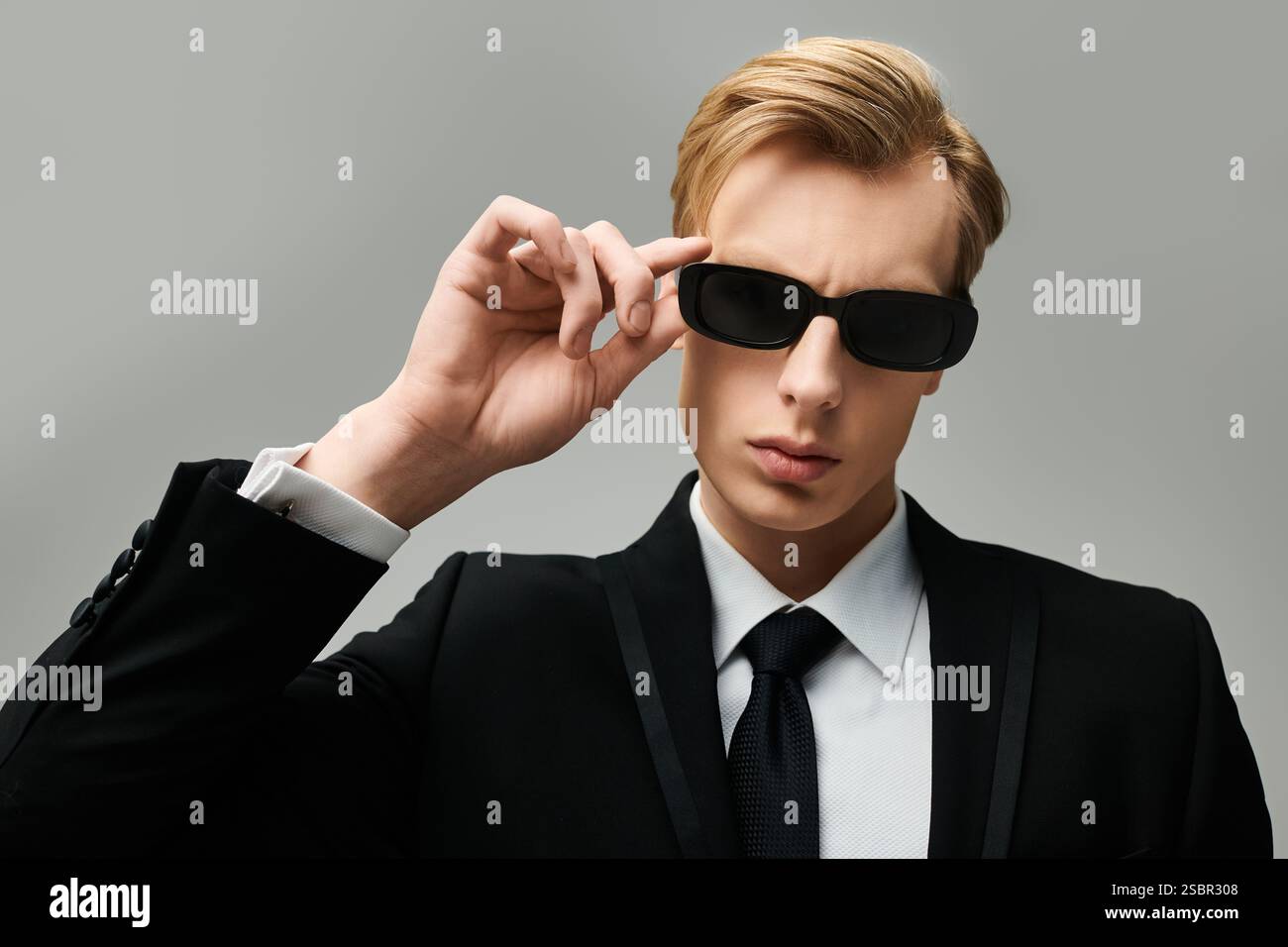 Striking young man wearing sunglasses and a suit exudes confidence in a ...
