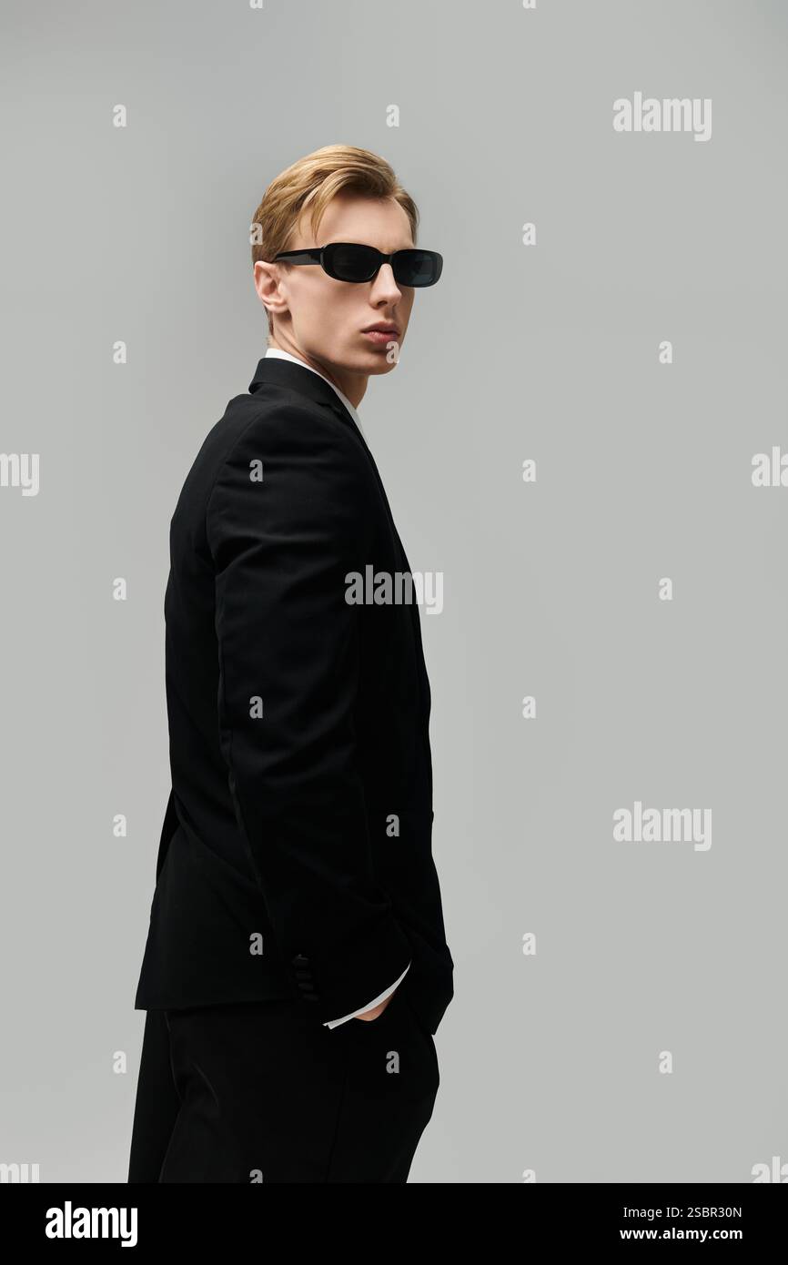A stylish young man in sunglasses and a sleek black suit exudes ...