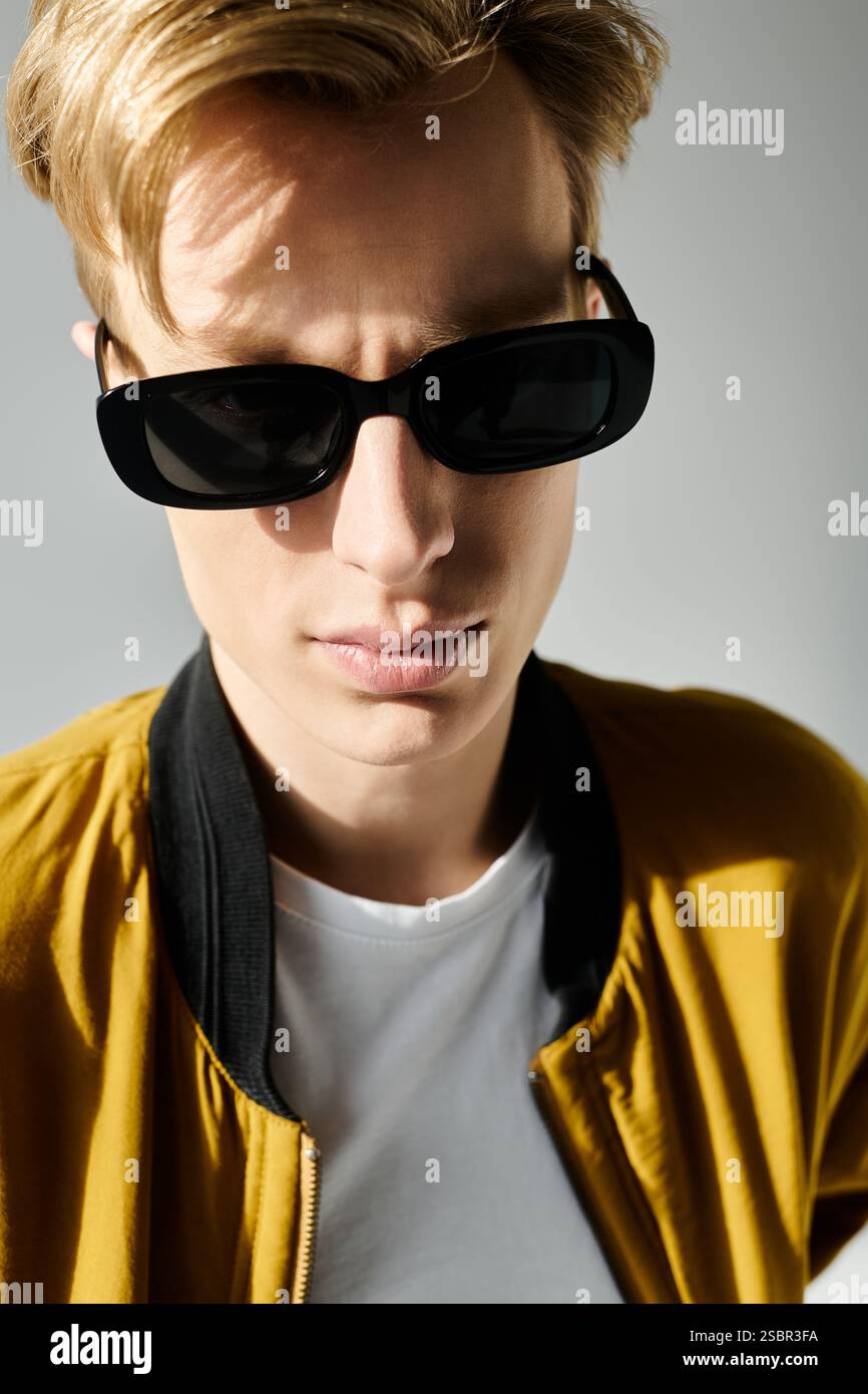 A young handsome man gazes confidently while wearing sunglasses and a ...
