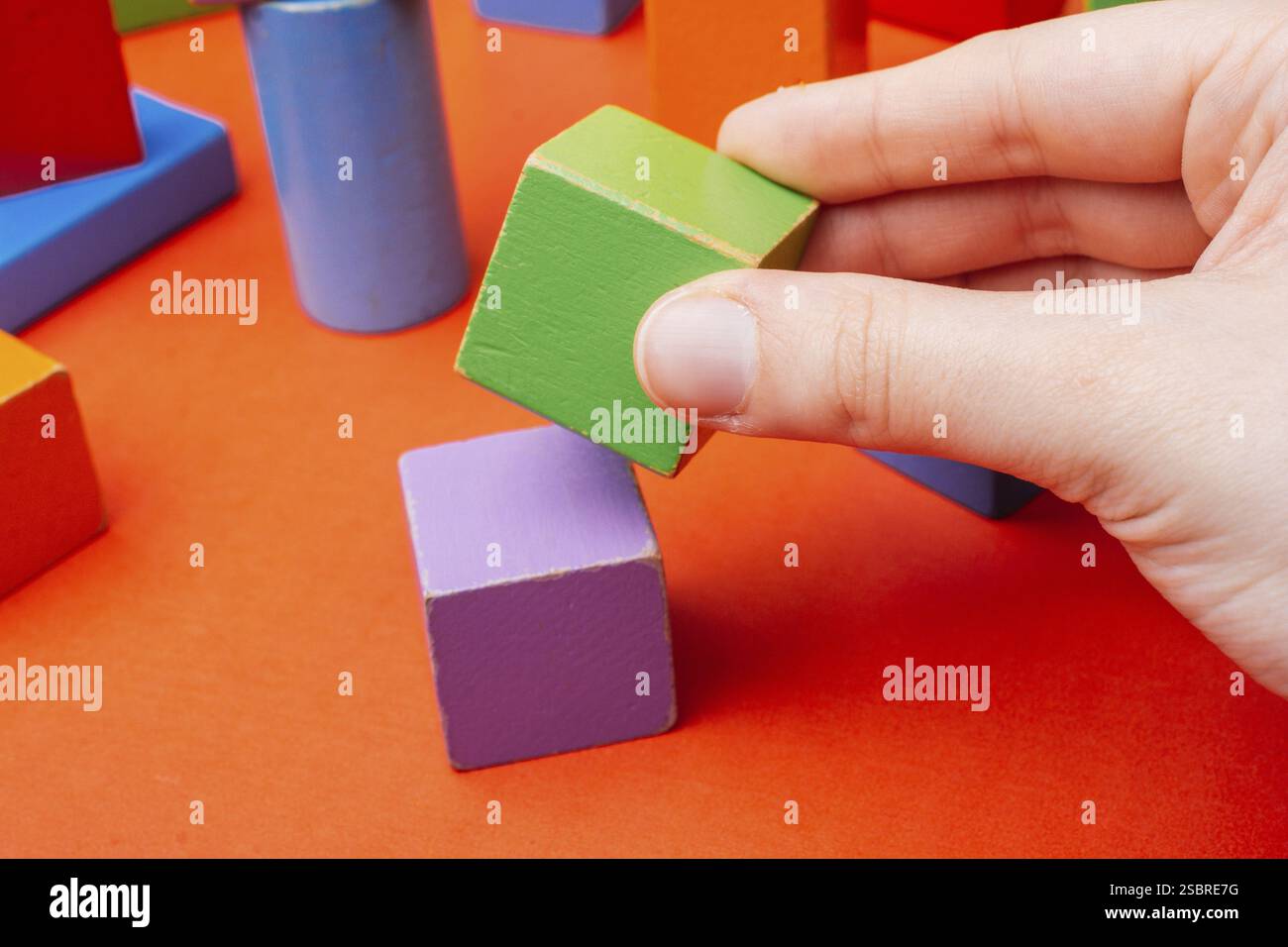 Hand building tower with colorful building blocks Stock Photo