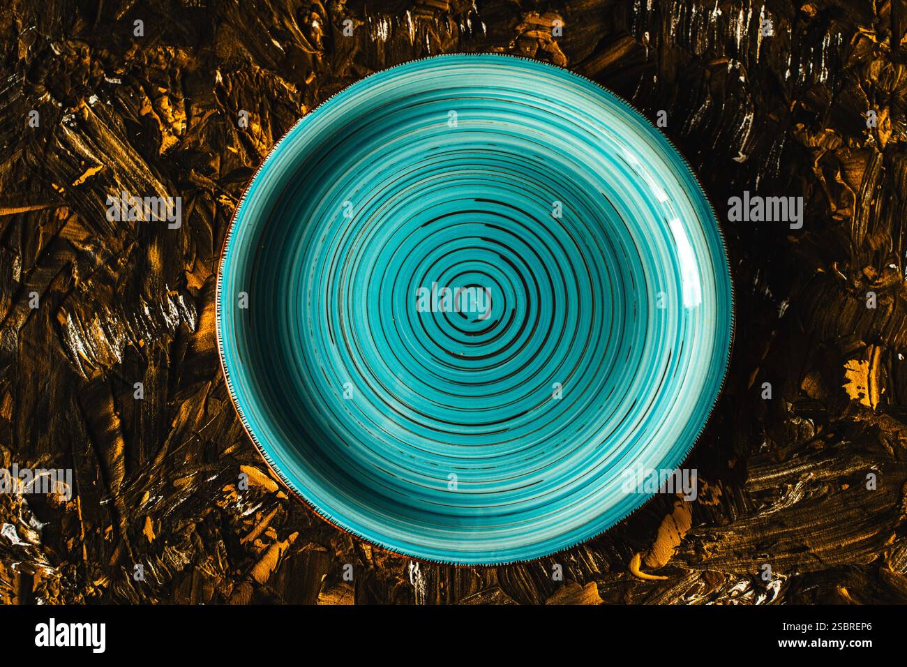 Turquoise plate empty on brown with gold background. Top view, space for text. High quality photo Stock Photo