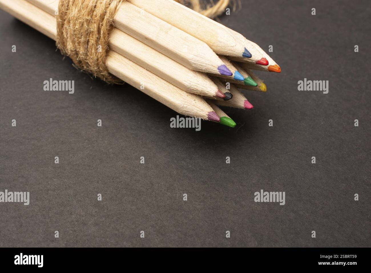 Bundle of colored pencils wrapped with string on black Stock Photo - Alamy