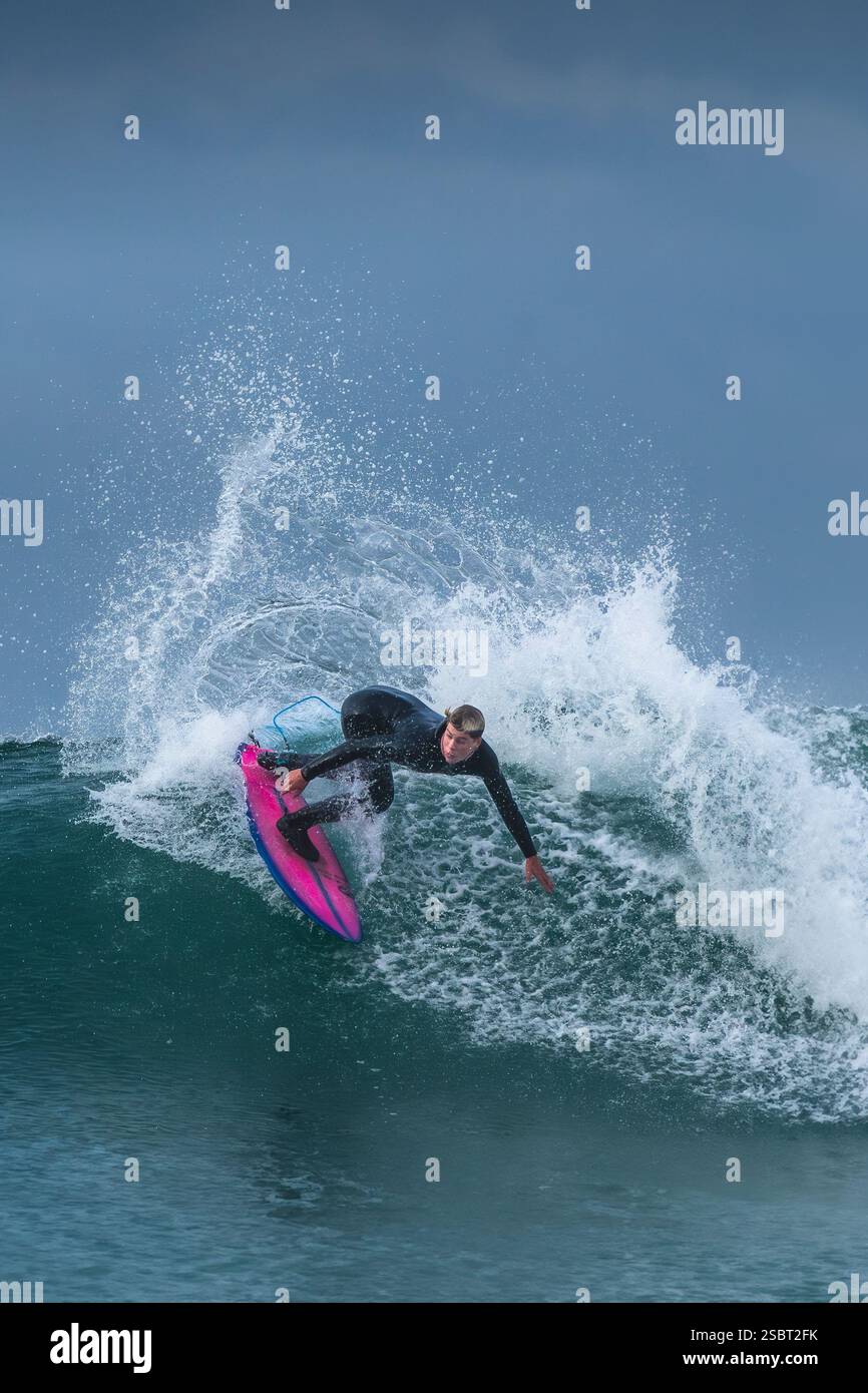 A surfer riding a wave at Fistral in Newquay in Cornwall in the UK ...