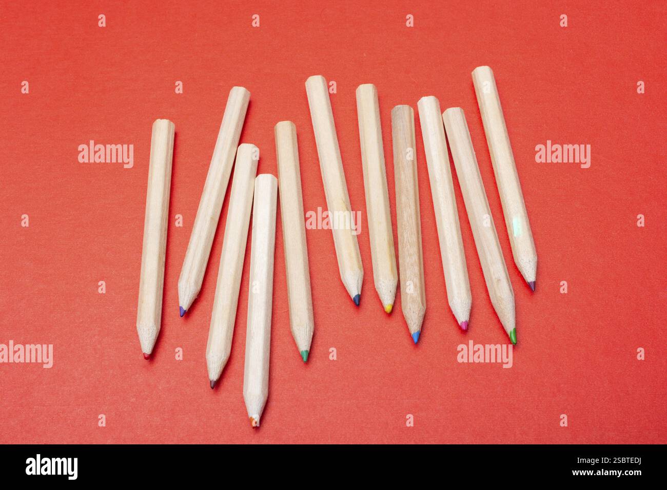 Colored pencils on red background. Many different colored pencils Stock Photo