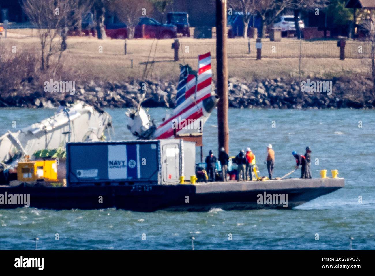 Parts of a plane are lifted from the water near the wreckage site in ...
