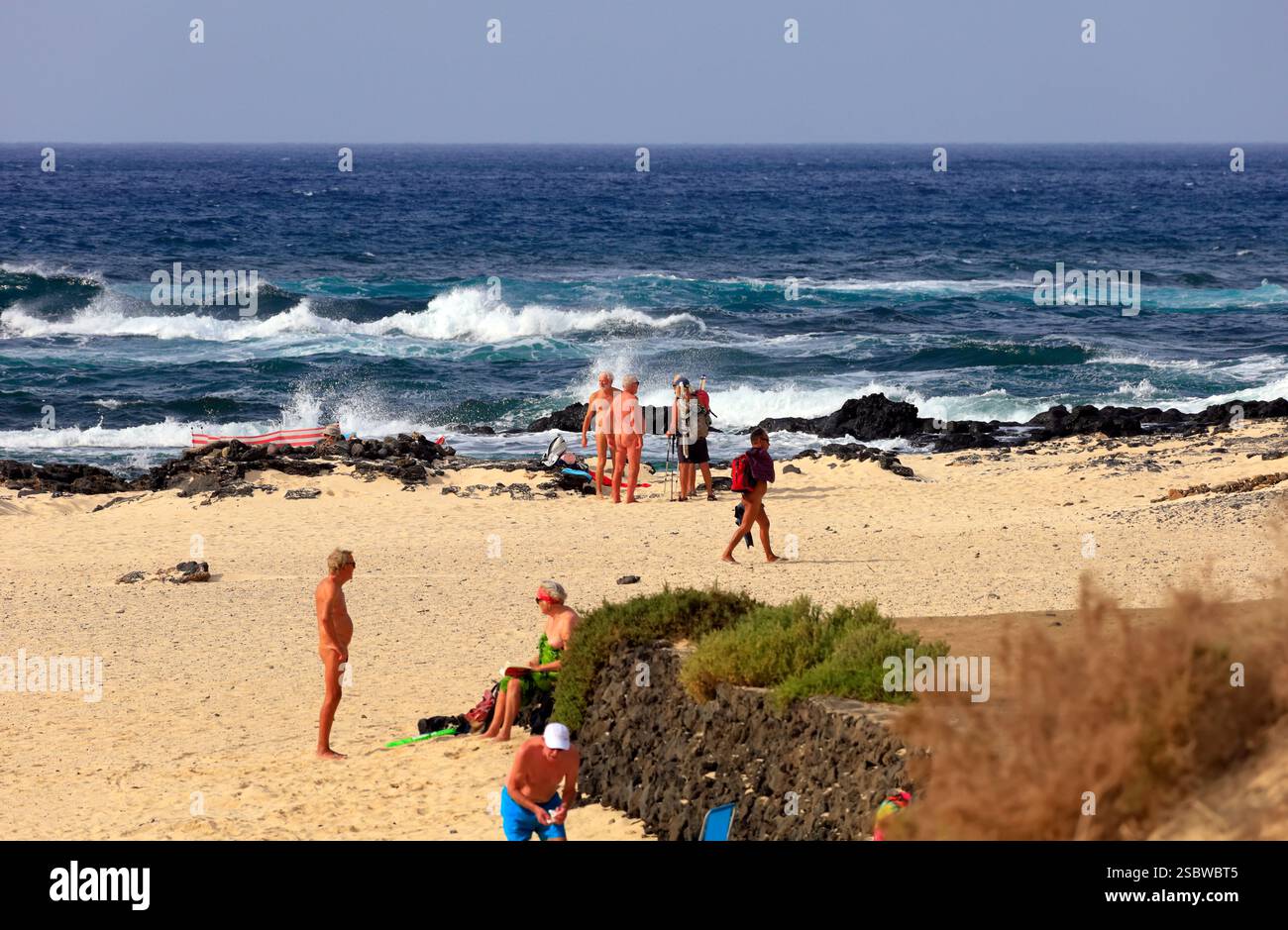Nudist beach with groups of naked people against Atlantic shoreline