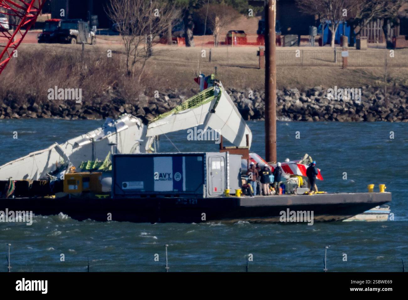 A piece of wreckage is lifted from the water onto a salvage vessel ...
