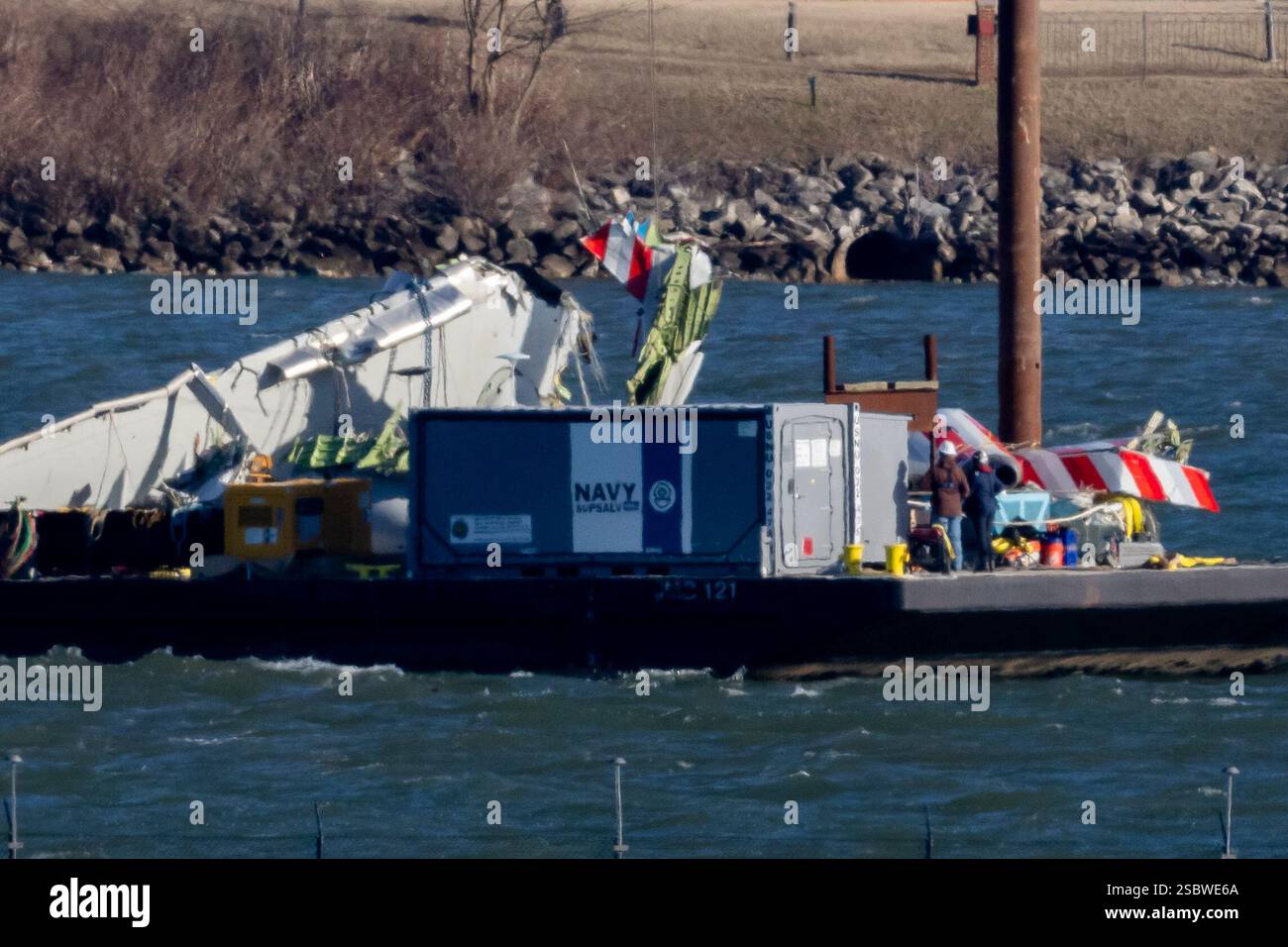 A piece of wreckage is lifted from the water onto a salvage vessel ...