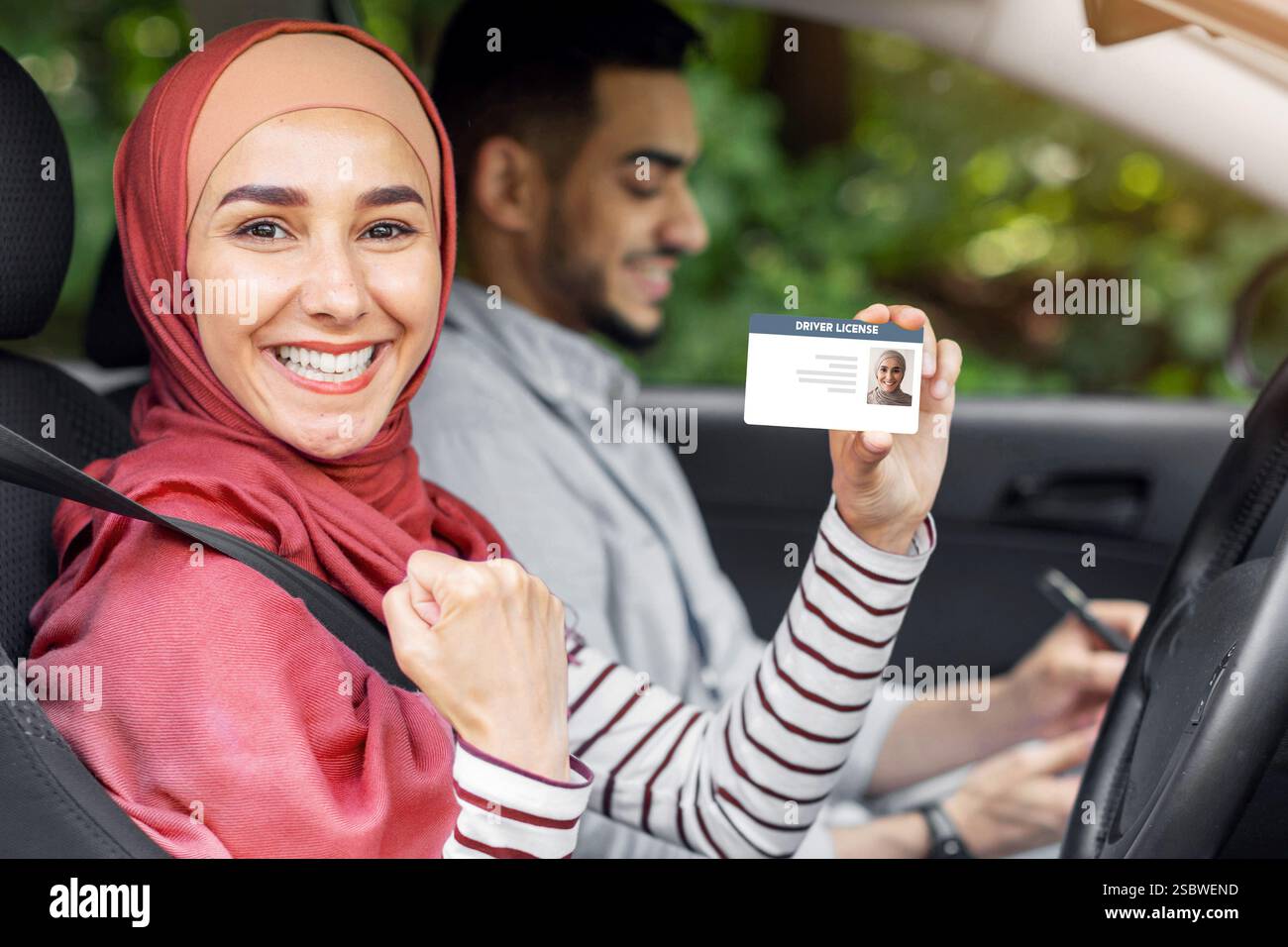 Glad muslim woman in hijab show driving license and fist in open door ...