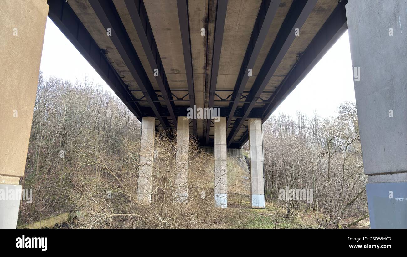 Underneath a motorway bridge over a river. Edinburgh bypass over Water of Leith. Concrete structure. Unusual underside view - Smartphone Captured Stock Image