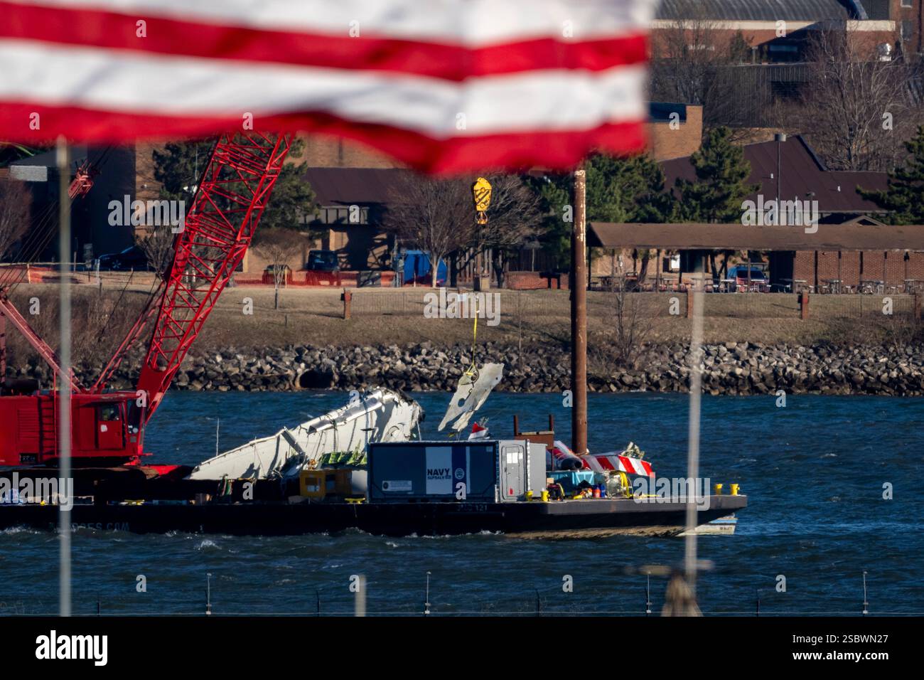 A piece of wreckage is lifted from the water onto a salvage vessel ...
