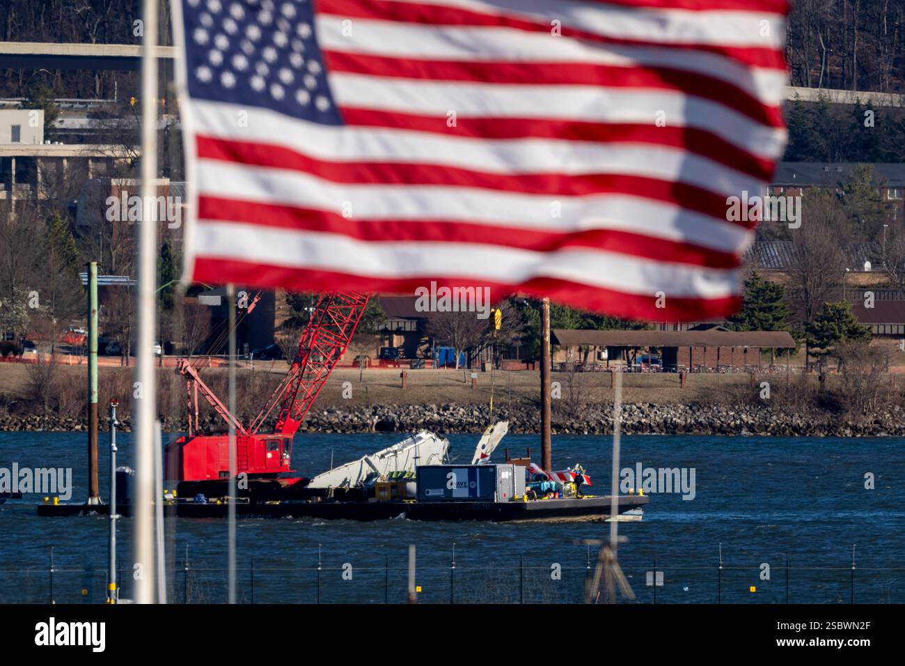 A piece of wreckage is lifted from the water onto a salvage vessel ...