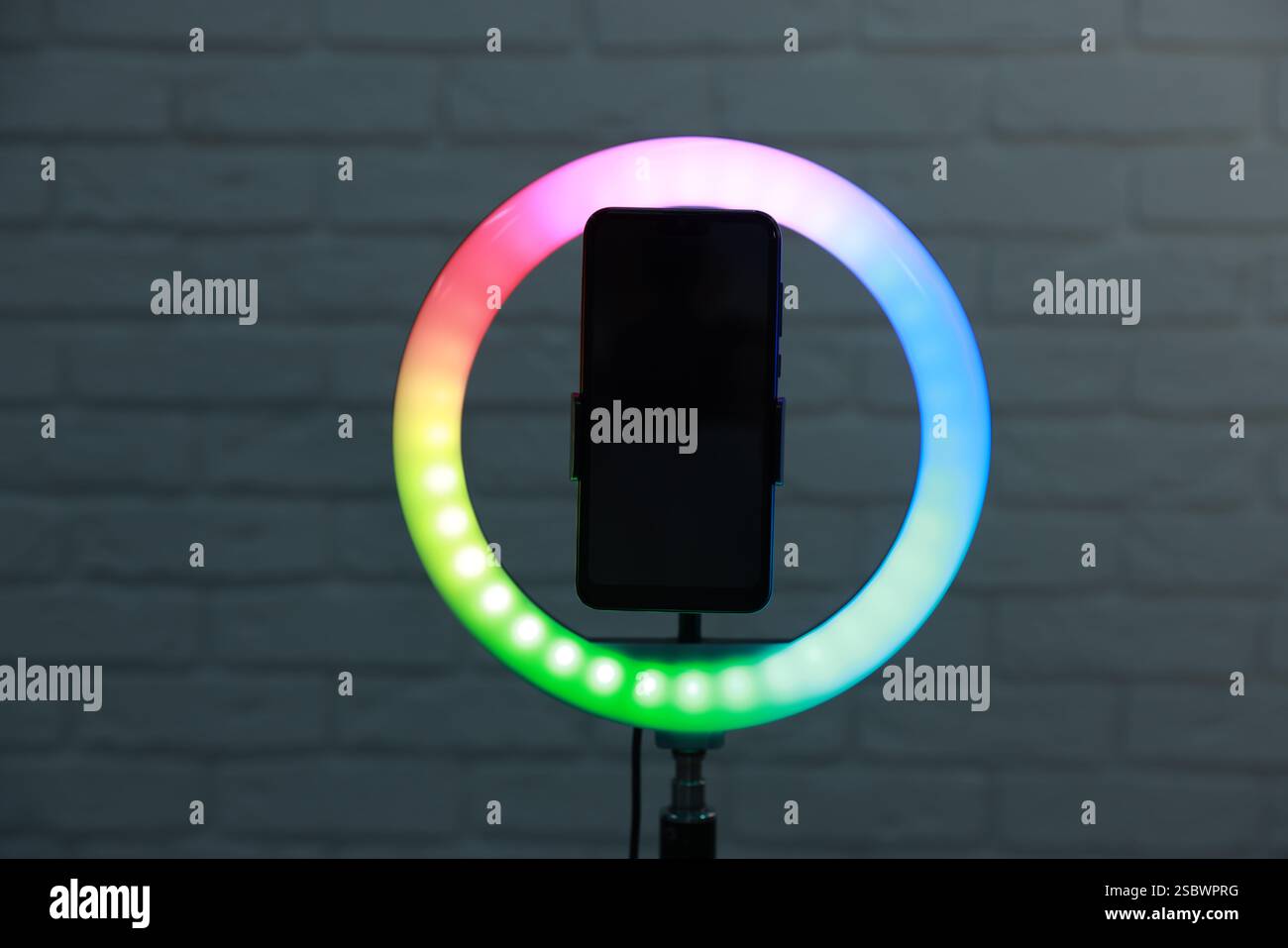 Ring lamp with smartphone against brick wall Stock Photo