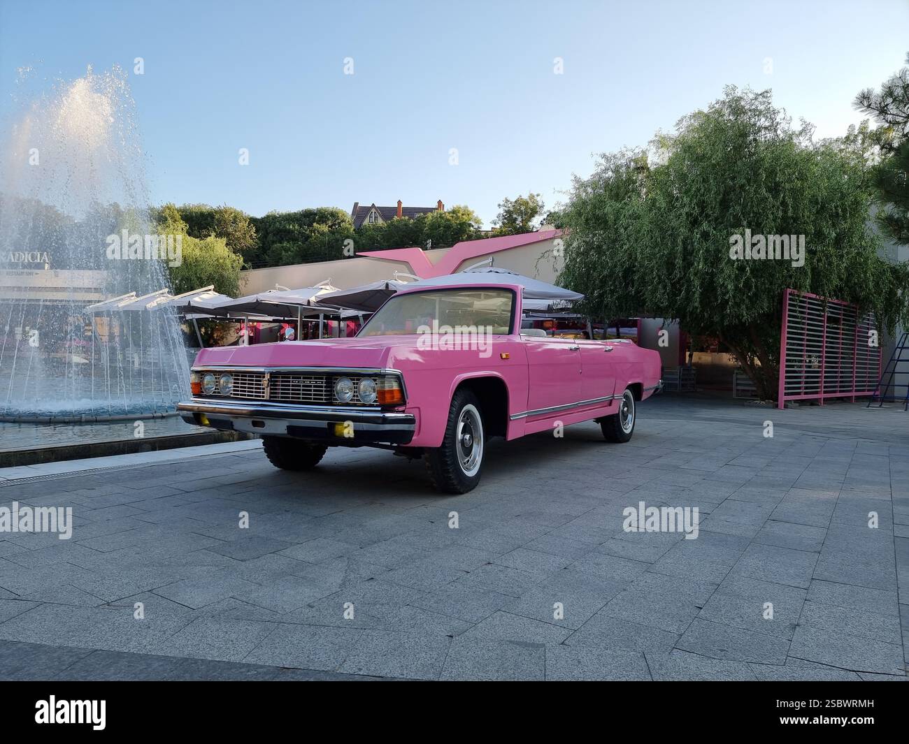 Bright pink classic Soviet car Chaika next to a fountain in Odesa, Ukraine - Smartphone Captured Stock Image