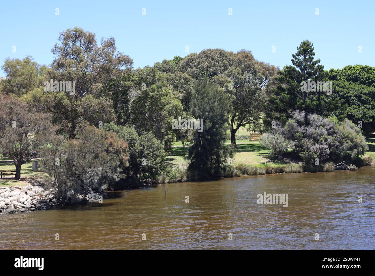 landscaped park on riverbank  under cloudless deep blue sky Stock Photo
