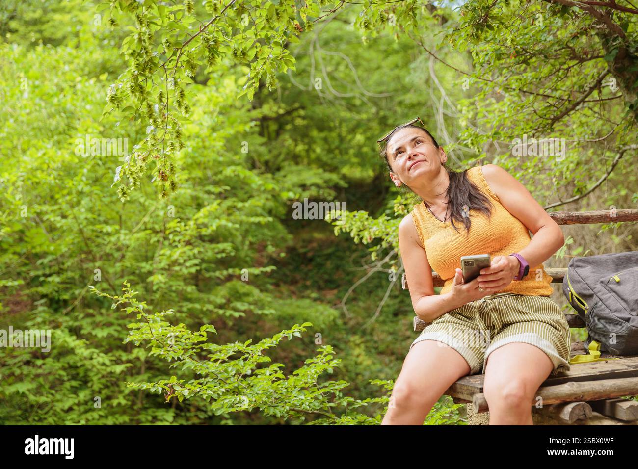 Woman using smartphone for pathfinding in forest Stock Photo