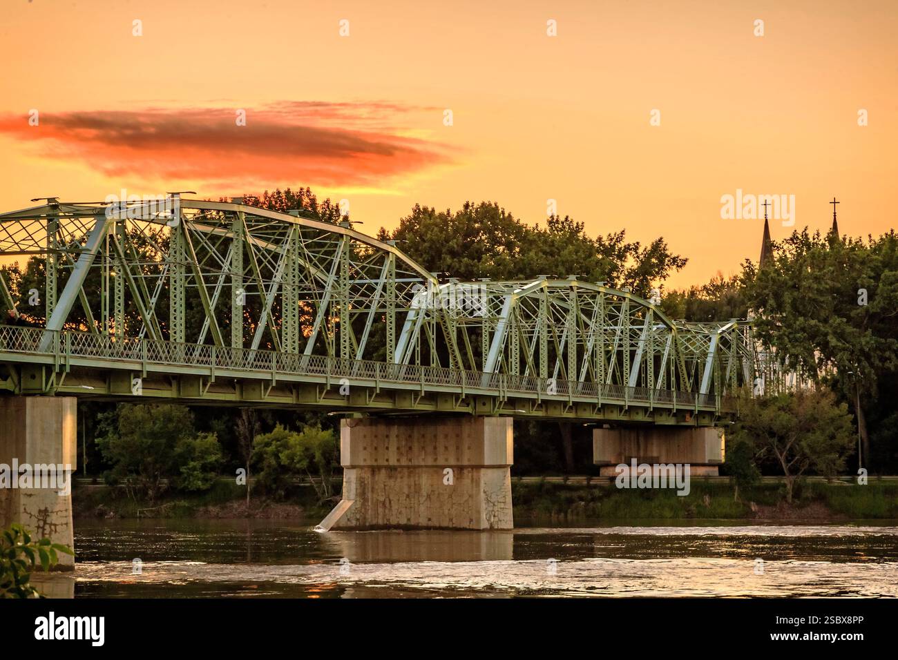 Bridge over a river with a sunset in the background. The bridge is ...