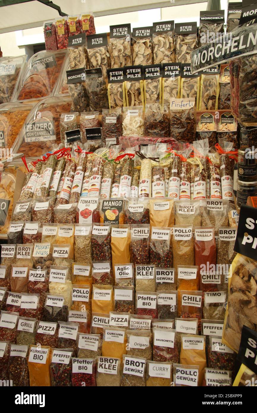 A photo of a bustling street market stand full with spices and mushrooms from all over the world with their names written in German language. Stock Photo