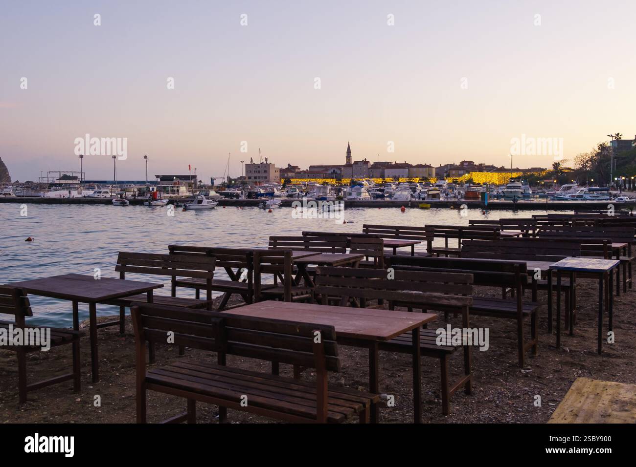 Empty waterfront dining area at sunset, Mediterranean Sea, off-season, deserted beach, old town in background Stock Photo