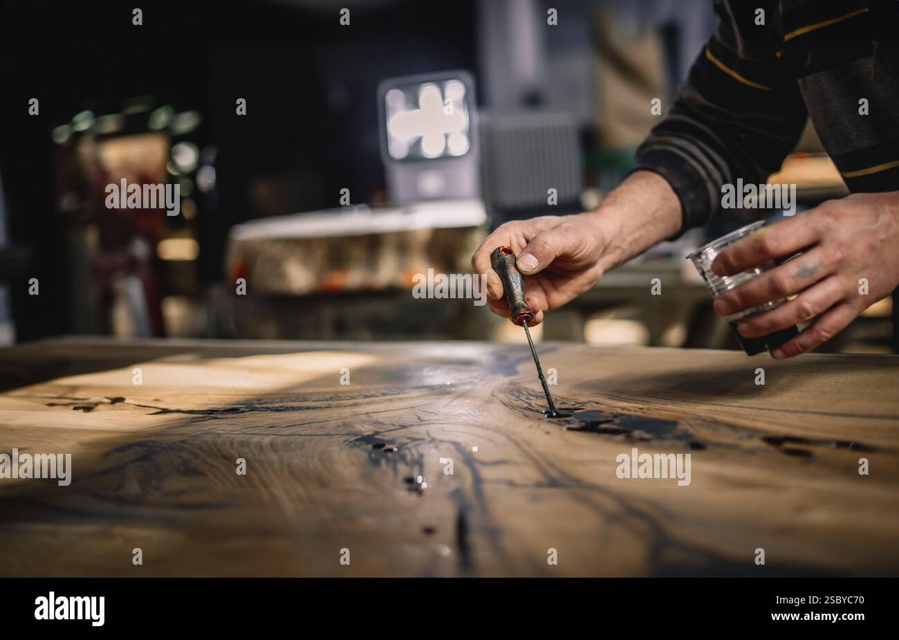 Close-up of hands expertly applying a tool to a wood surface under warm ...