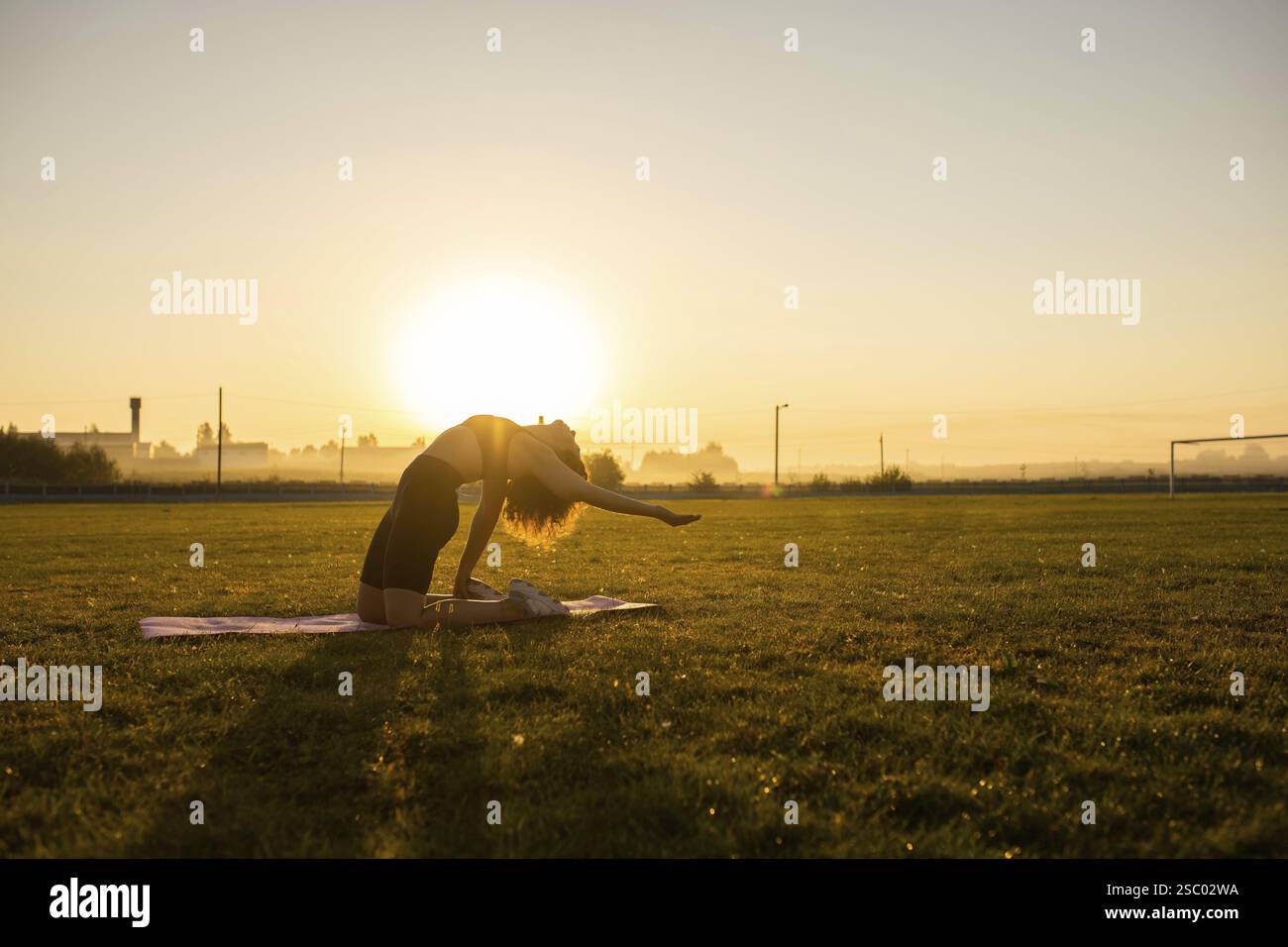 Silhouette of a person reaching forward in a yoga pose during sunrise ...