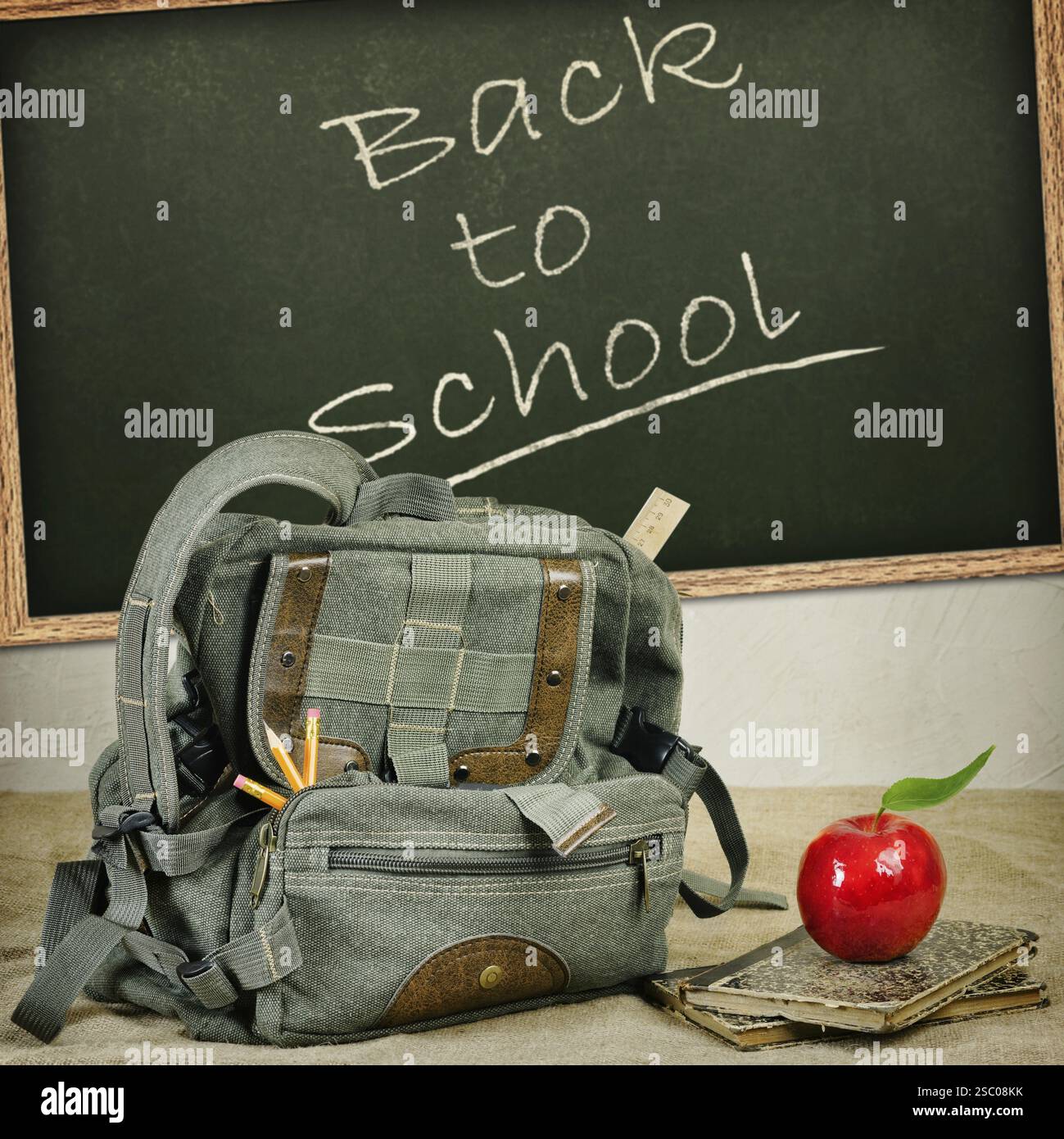 Still life with an old backpack, books and red apple Stock Photo - Alamy