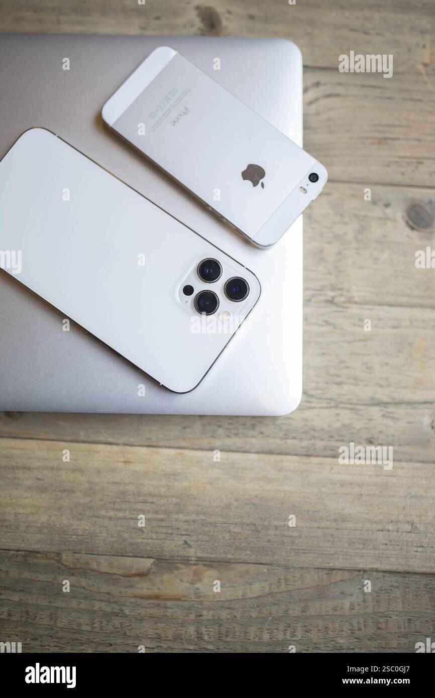 White iPhone with a visible camera module on a wooden table Stock Photo