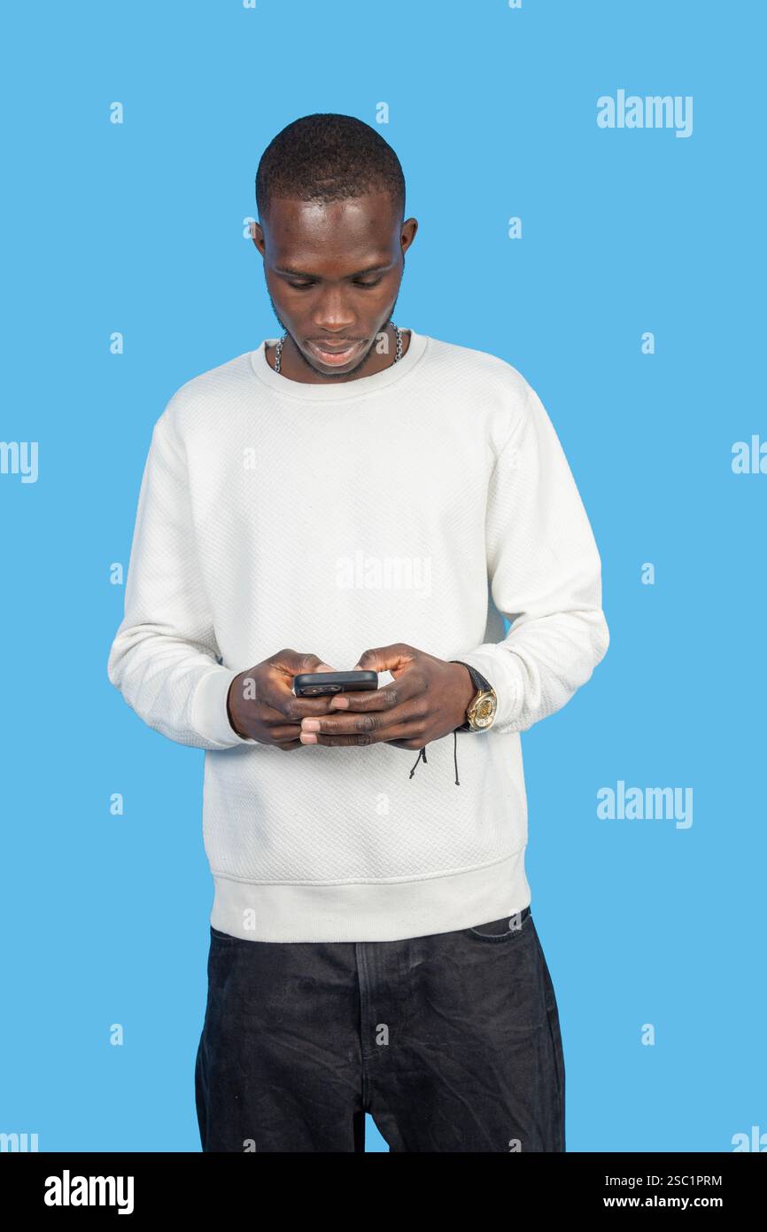 Young man using smartphone on blue background: concentrated man browsing social media Stock Photo