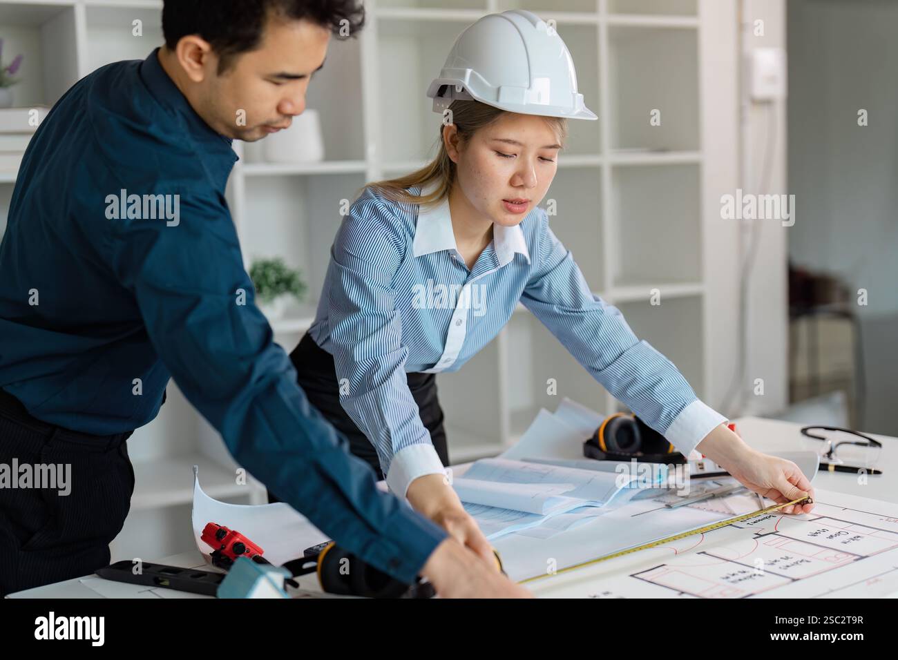 Diverse architects measuring and reviewing construction design plans. Stock Photo