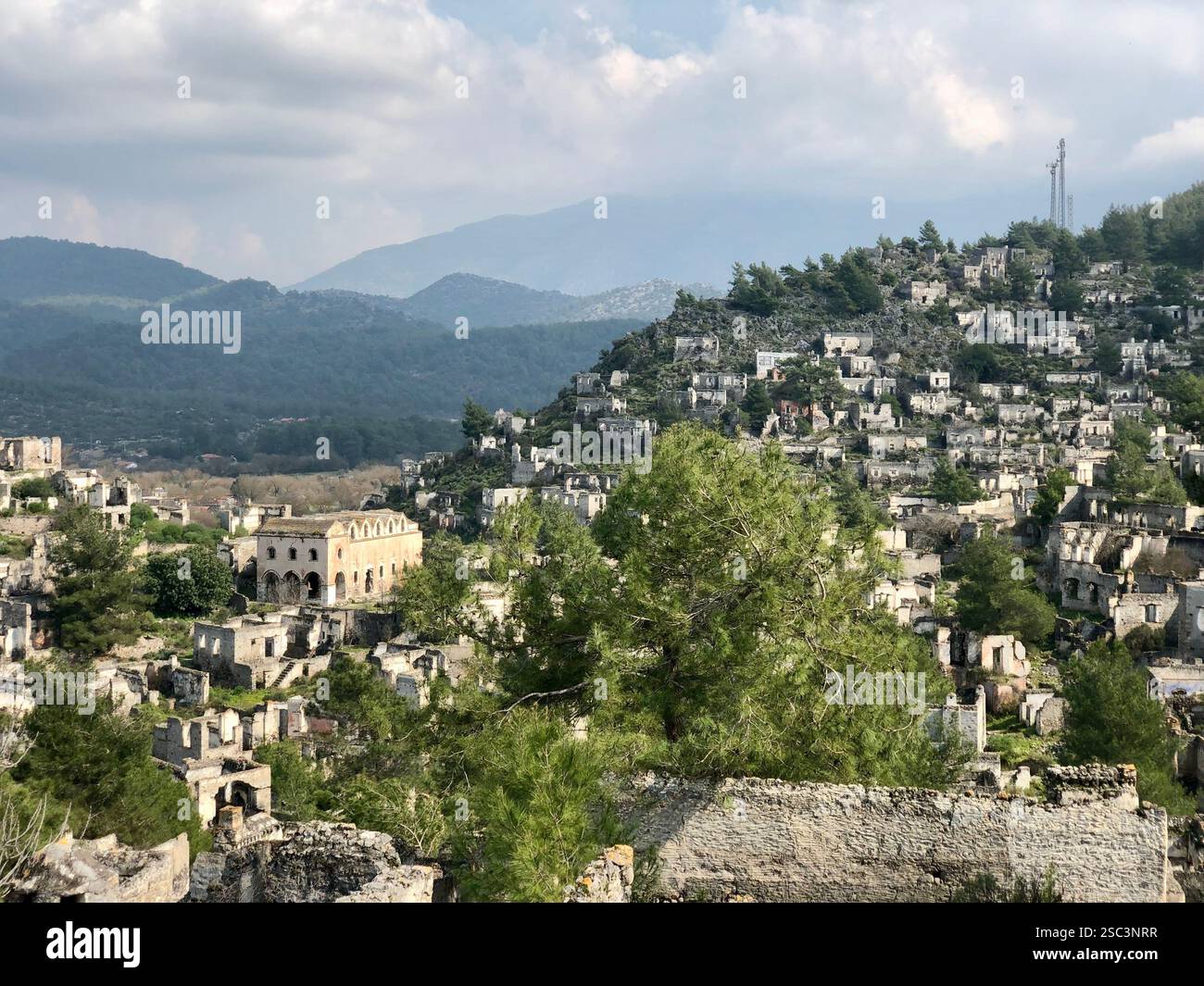 An abandoned ghost village in the hills of Turkey surrounded by mountains and trees - Smartphone Captured Stock Image