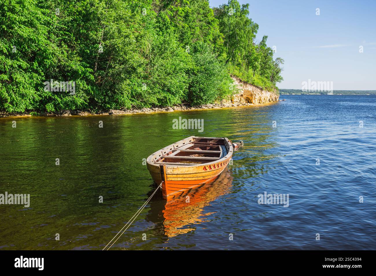 wooden boat on the river bank on forest background and blue sky ...