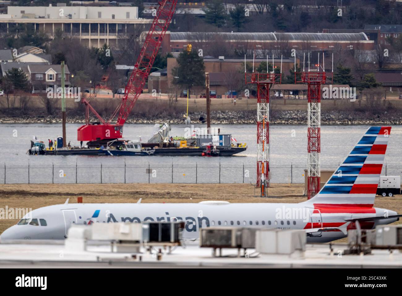 Salvage crews lift a piece of wreckage from the water, as an aircraft ...