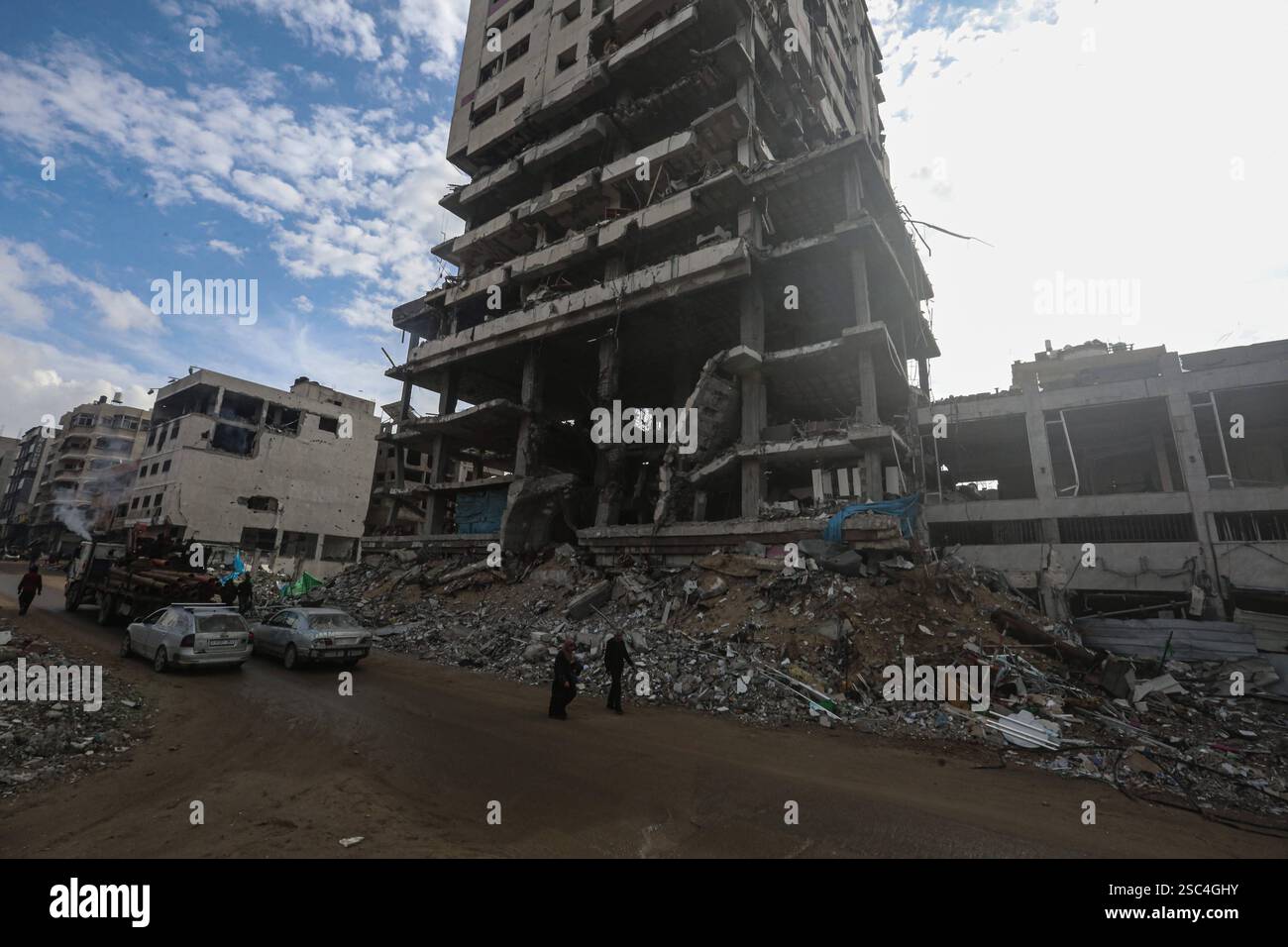 Palestinians walk past collapsed buildings along the streets of Gaza ...