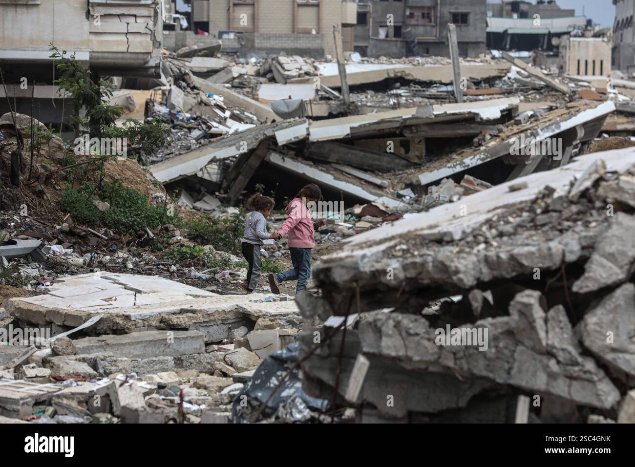 Palestinians walk past collapsed buildings along the streets of Gaza ...