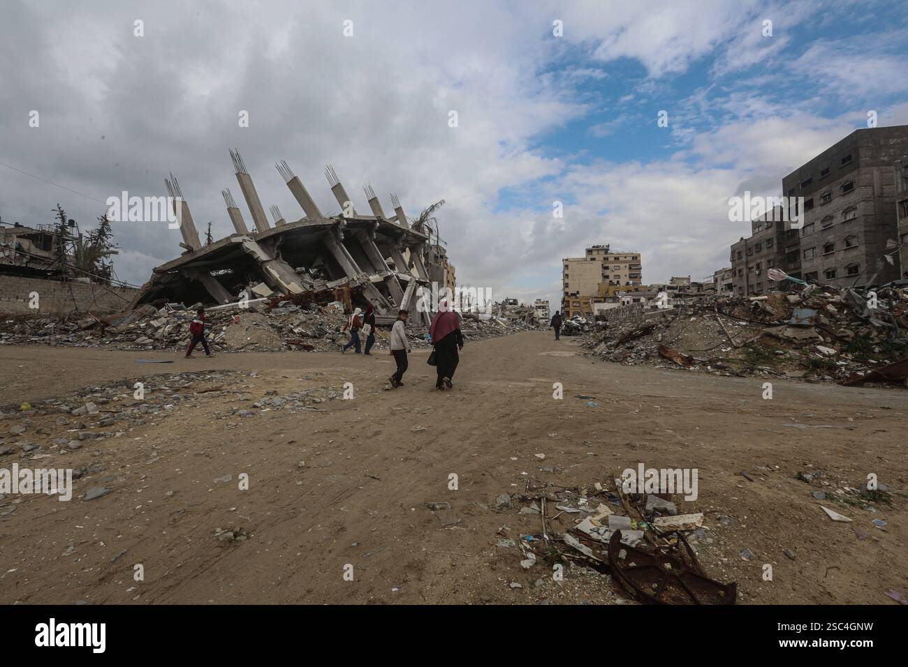 Palestinians walk past collapsed buildings along the streets of Gaza ...