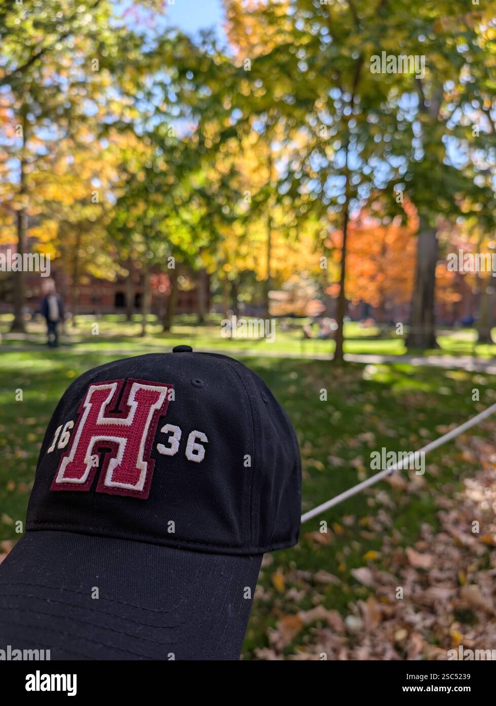 Harvard University baseball cap in the forground with |Harvard Yard, Harvard University, Boston, Massachuesetts, USA - Smartphone Captured Stock Image