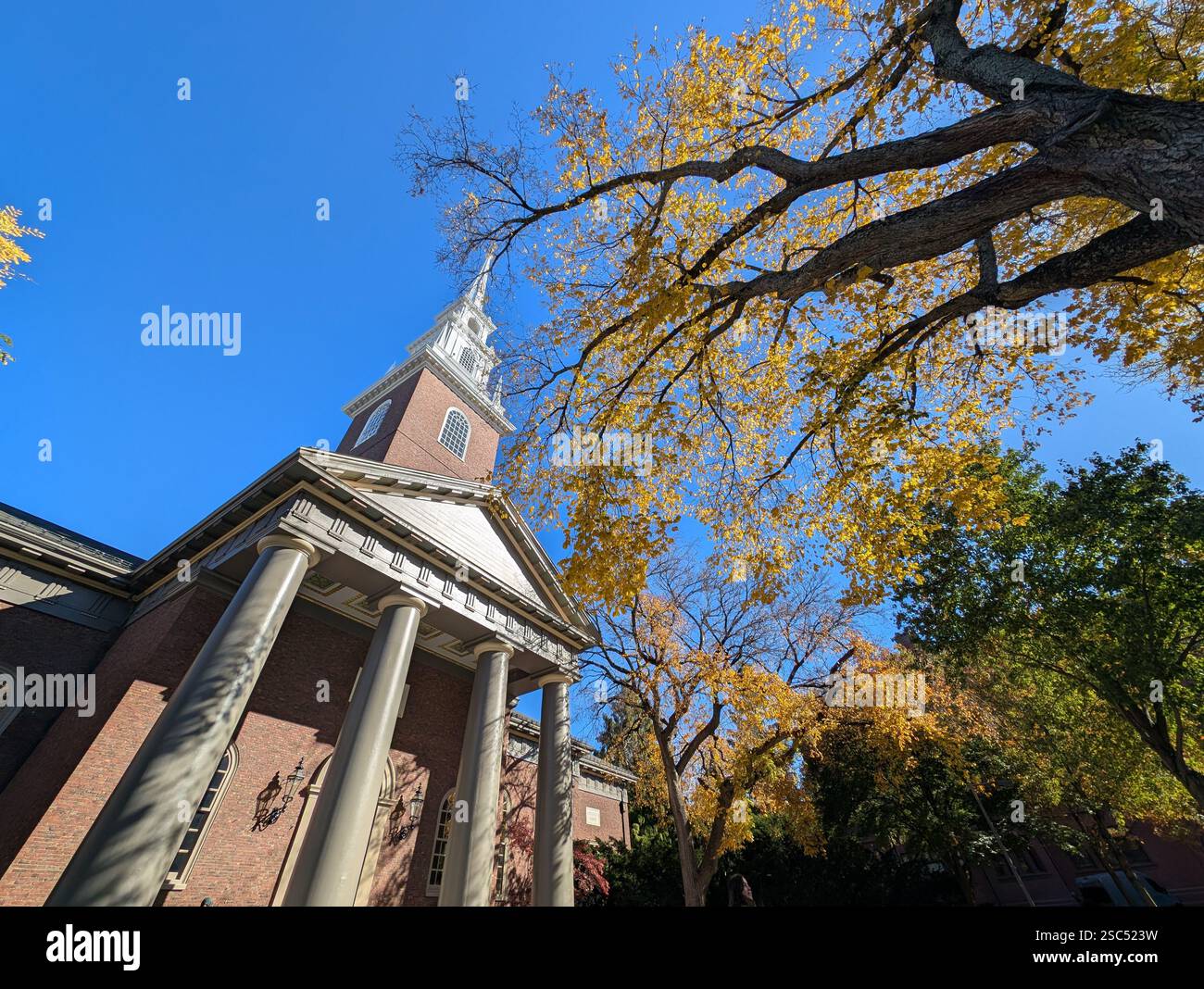 The Memorial Church of Harvard University is a building on the campus of Harvard University, with the steeple of the building, set against Blue Sky. - Smartphone Captured Stock Image
