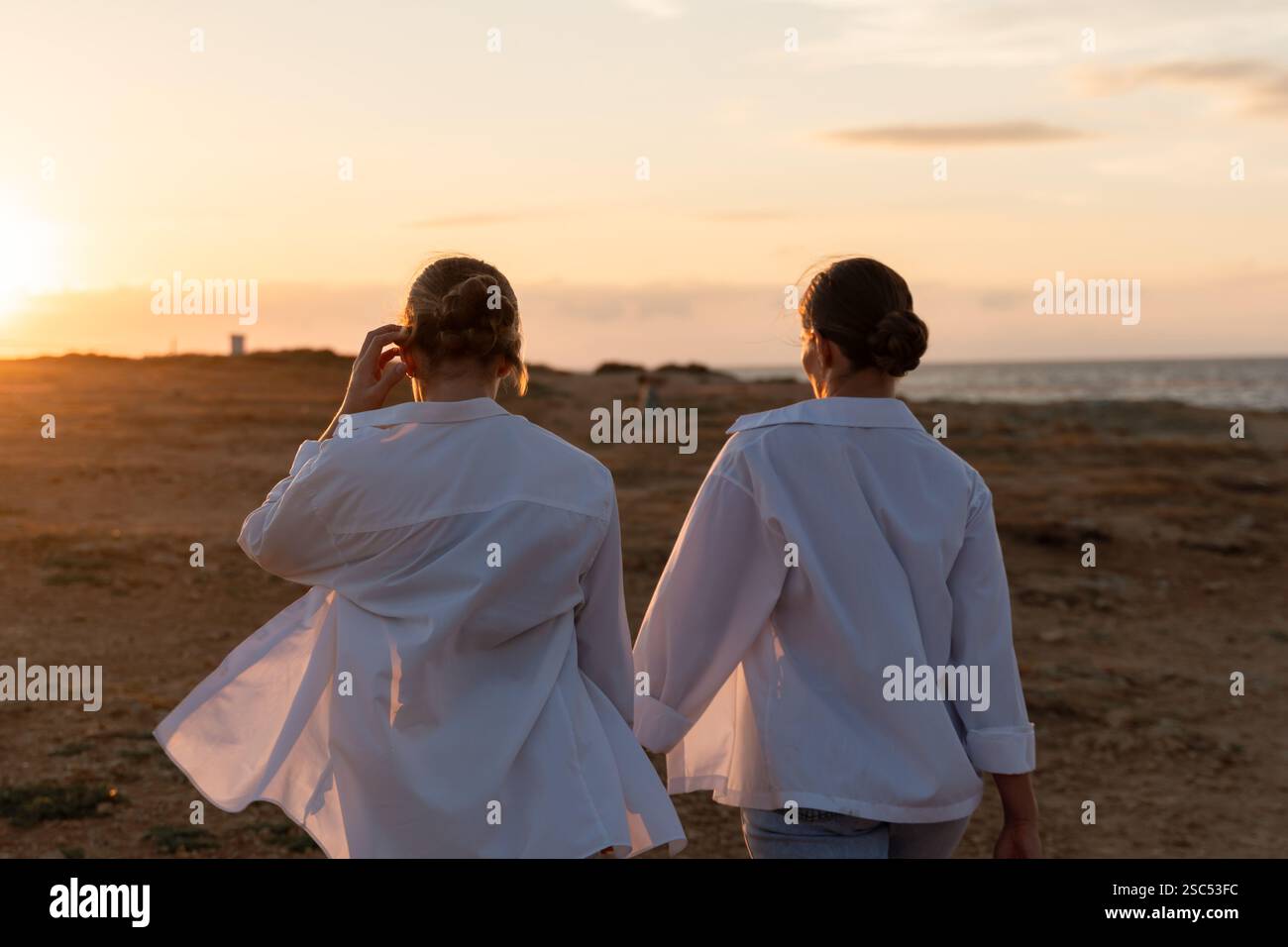 Couple Sunset Beach - Two women walk hand in hand towards a sunset on a ...