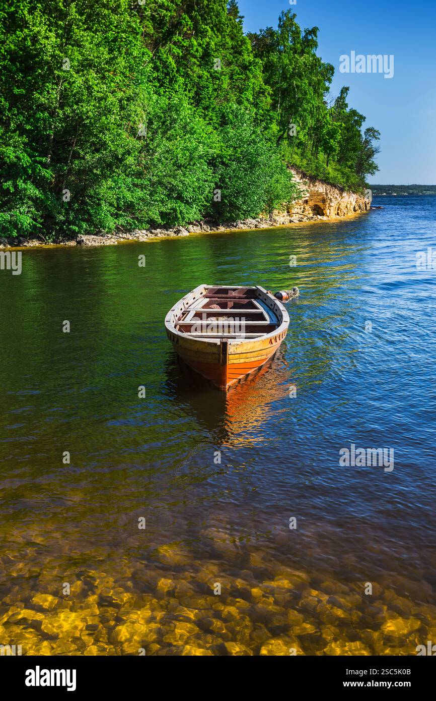 wooden boat on the river bank on forest background and blue sky ...