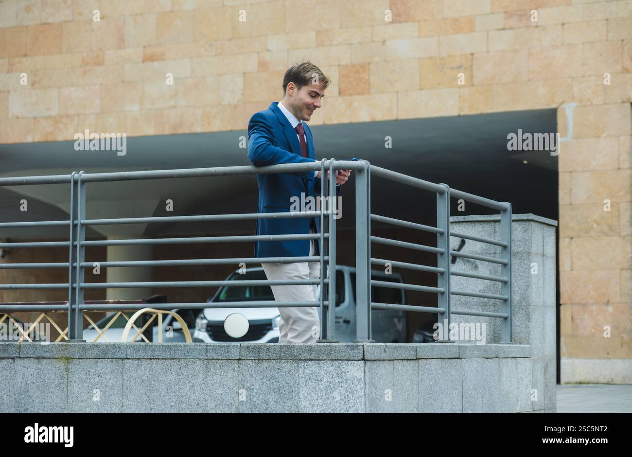 Businessman leaning on railing and using smartphone Stock Photo