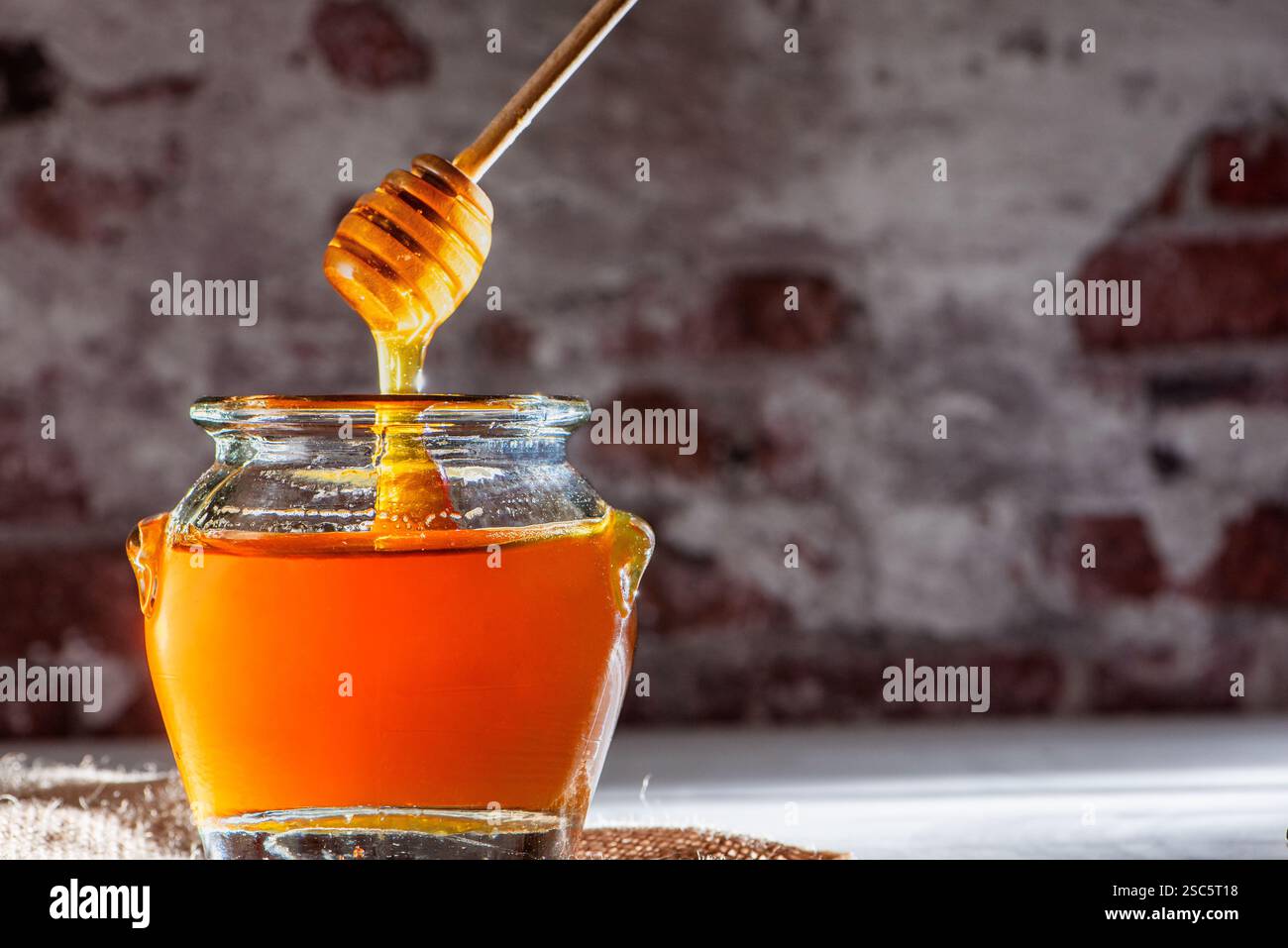Honey dipper coming out of a jar, dripping honey back into the jar ...
