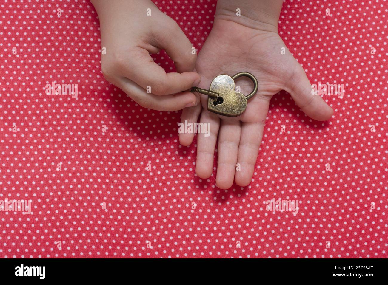 Hand holding a heart shaped lock and key on a red background Stock ...