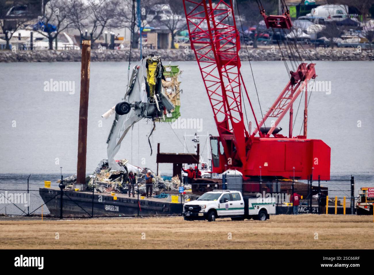 A crane offloads a piece of wreckage from a salvage vessel onto a ...