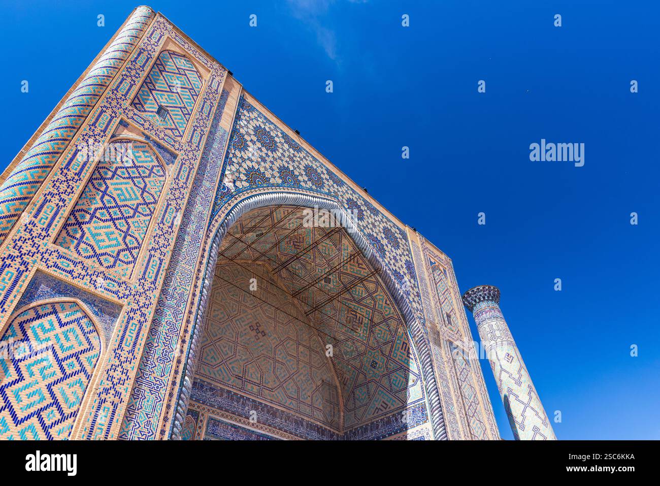 Portal and minaret of Ulugh Beg Madrasah under blue sky on a sunny day. Registan square, Samarkand, Uzbekistan Stock Photo