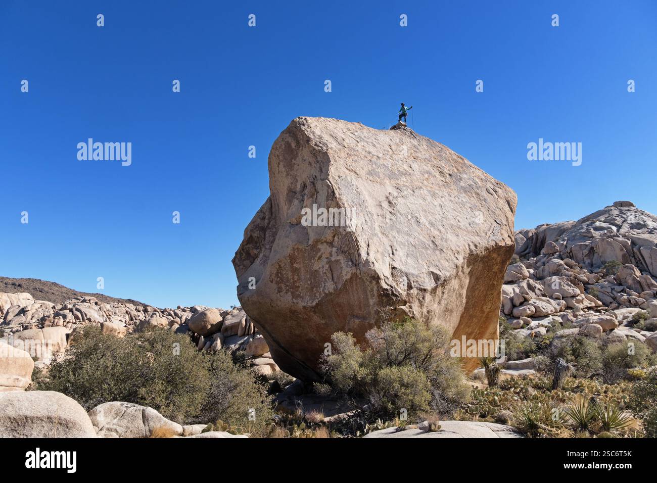 woman standing on top of the massive Don Juan Boulder in the Wonderland of Rocks area of Joshua Tree National Park Stock Photo