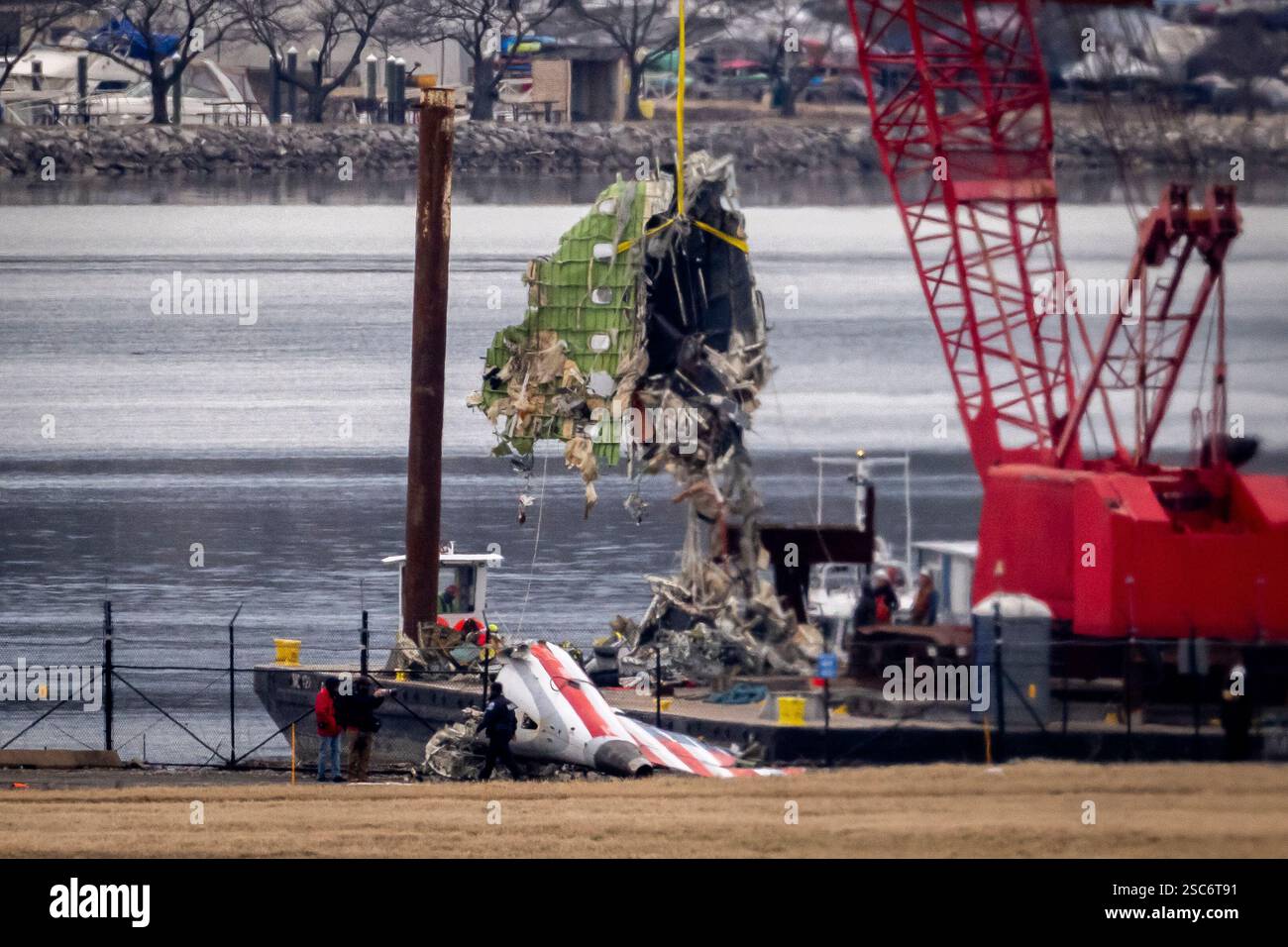 A crane offloads a piece of wreckage from a salvage vessel onto a ...