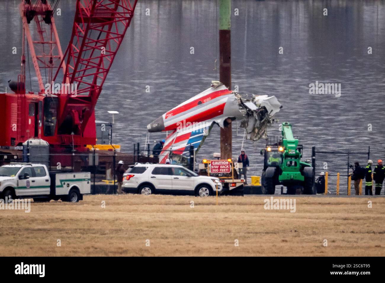 A crane offloads a piece of wreckage from a salvage vessel onto a ...